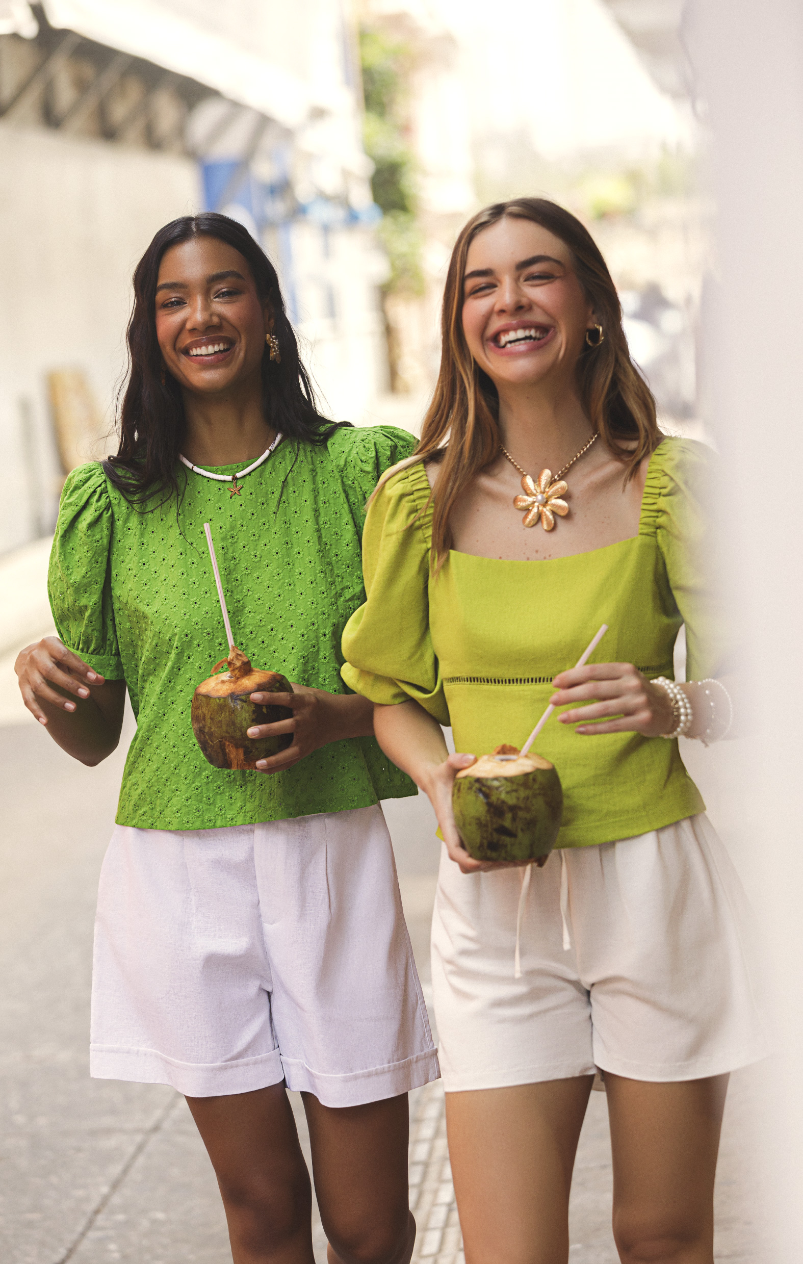 Dos mujeres luciendo outfits de verano y tomando bebidas tropicales para campaña de summer ELA 2025