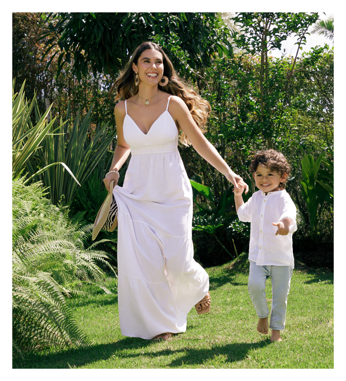 Mamá con su hijo vistiendo un vestido largo blanco de tiras y el niño un conjunto blanco de pantalón y camisa