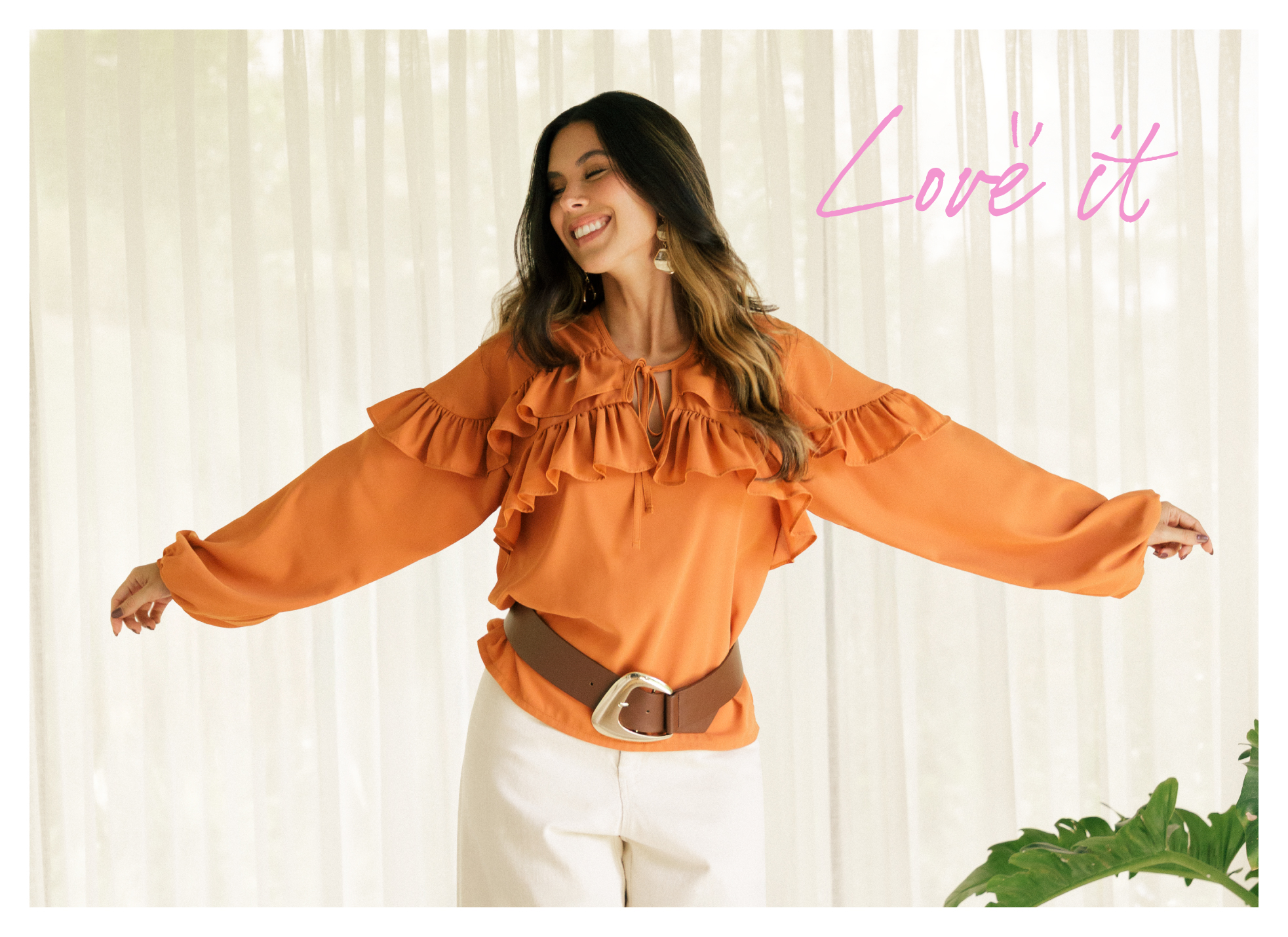 Modelo Daniela Salazar luciendo blusa naranja con boleros, maxi cinturón café con hebilla dorada y pantalón blanco