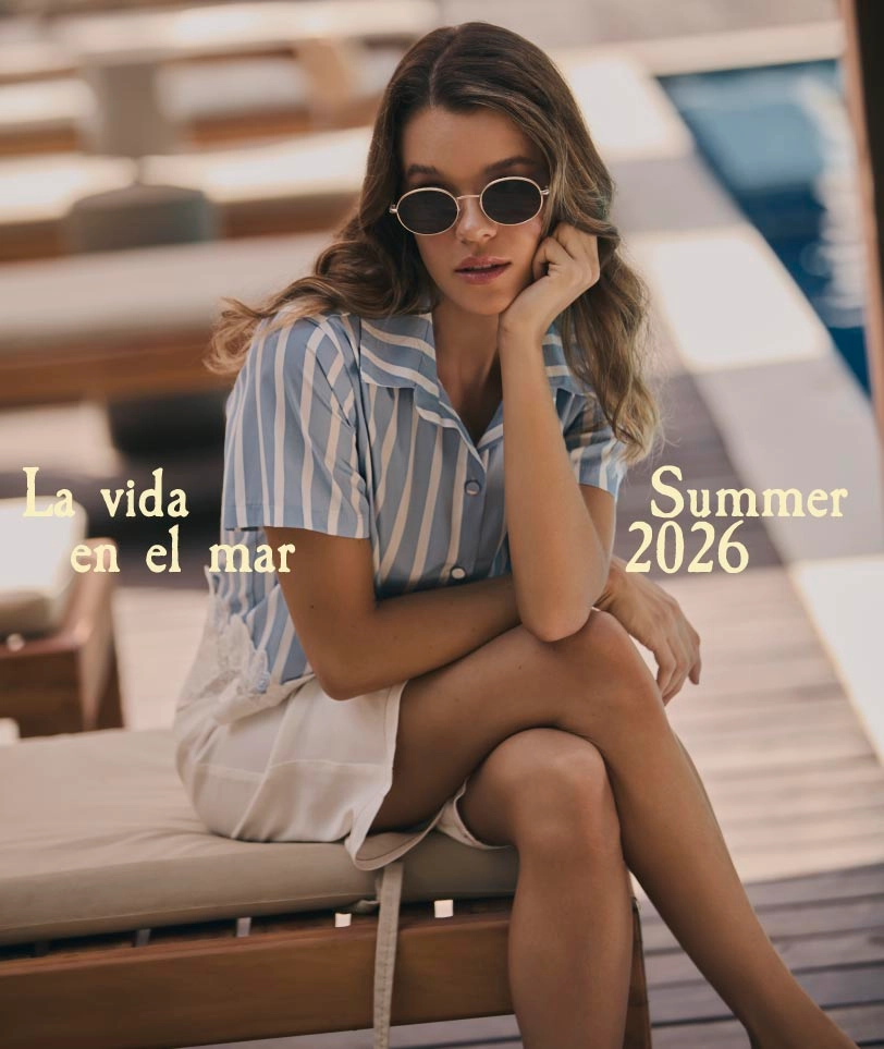 Mujer con camisa de rayas azul y blanco junto a piscina usando ropa fresca y ligera para verano.