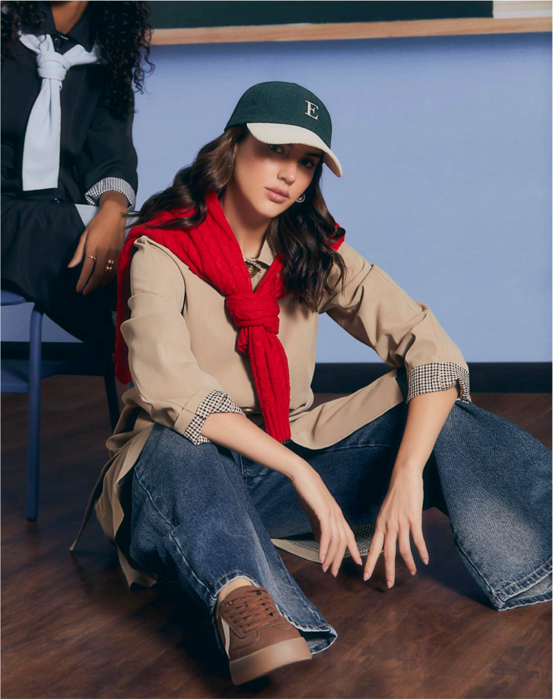 Mujer con camisa beige, jeans wide leg, suéter rojo sobre los hombros, gorra y tenis café.
