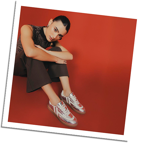 Mujer con tenis plateados y outfit marrón oscuro, estilo moderno y casual de la ultima colección de la marca ela