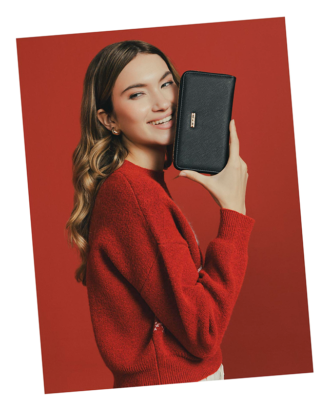 Mujer con suéter rojo y billetera negra, estilo moderno y versátil.