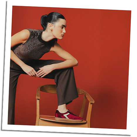 Modelo mujer con tenis rojos y top oscuro, look urbano femenino sobre fondo rojo de la marca ela