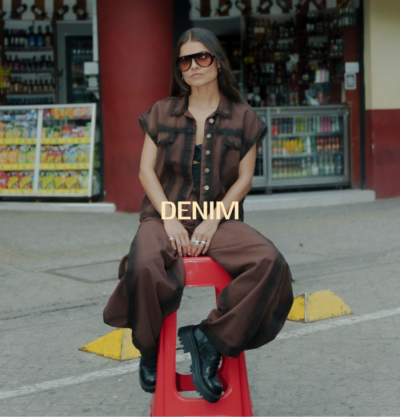 Mujer con chaleco denim café, jean wide leg y botas negras y gafas de sol 