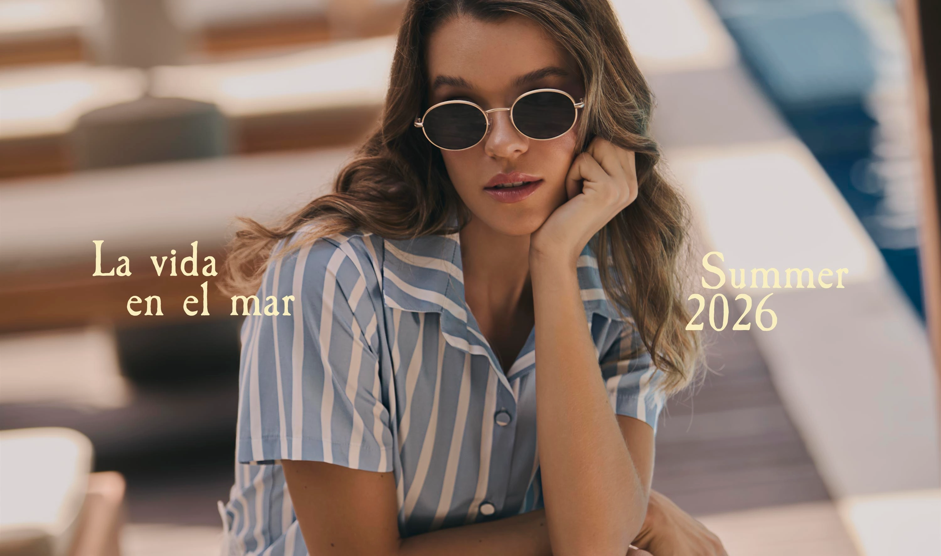 Mujer con camisa de rayas azul y blanco junto a piscina usando ropa fresca y ligera para verano.